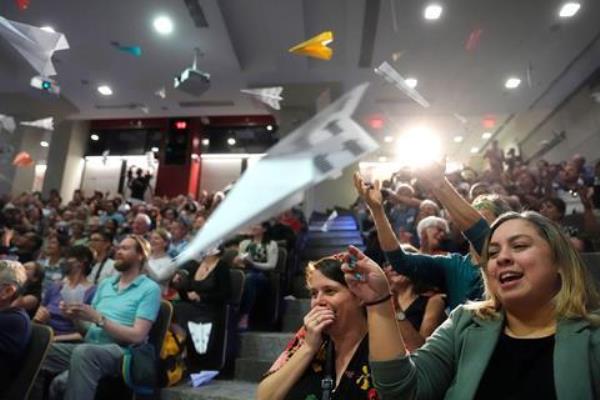 An audience throwing paper planes