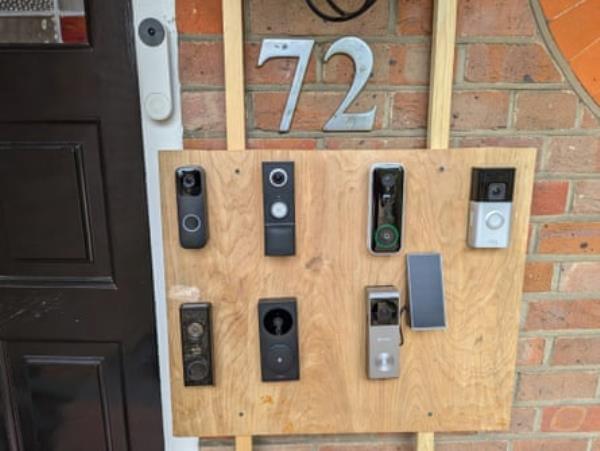 A plank of wood with 8 video doorbells attached to it