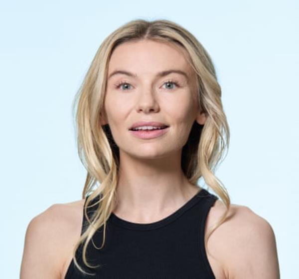 A portrait of Georgia Toffolo, with long blo<em></em>nde hair, and wearing a black vest top, shot against a pale blue background