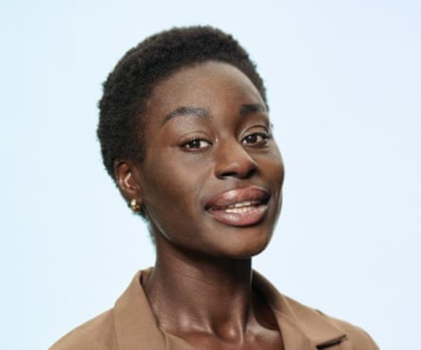 Aramidé o<em></em>nashoga with short dark Afro hair, shot against a pale blue background